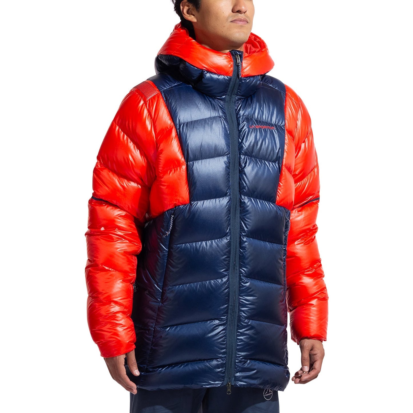 A person wears the La Sportiva Supercouloir Down Parka Men's—a high-altitude jacket in blue with bright red sleeves, shoulders, and hood—standing against a white background to display its superior packable warmth.
