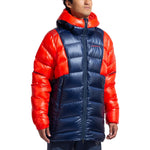 A person wears the La Sportiva Supercouloir Down Parka Men's—a high-altitude jacket in blue with bright red sleeves, shoulders, and hood—standing against a white background to display its superior packable warmth.
