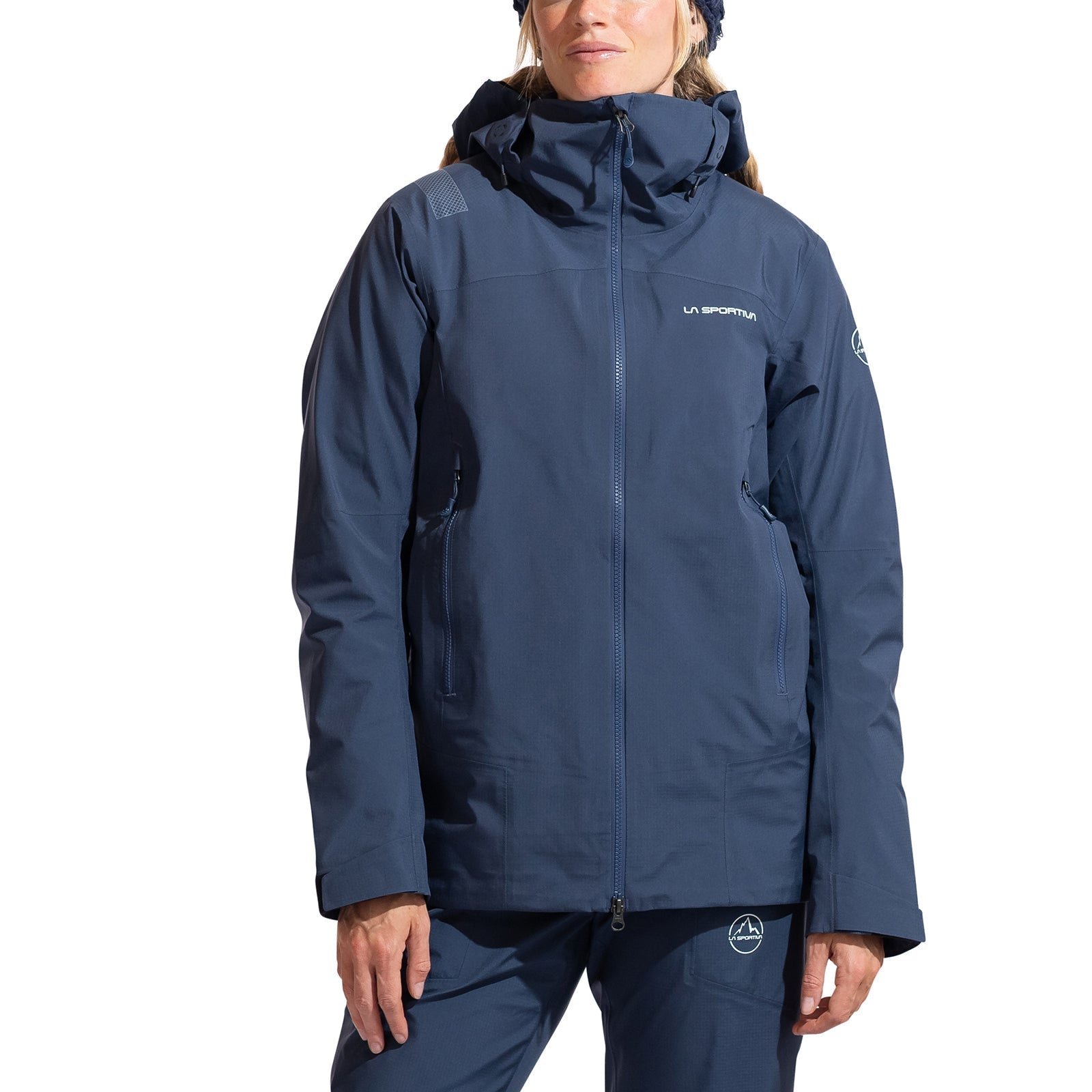 A woman wearing the La Sportiva Alpine Guide GTX Performance Jacket in navy blue, featuring a front zipper, visible pockets, and signature branding—perfect for technical mountaineering or alpine pursuits.