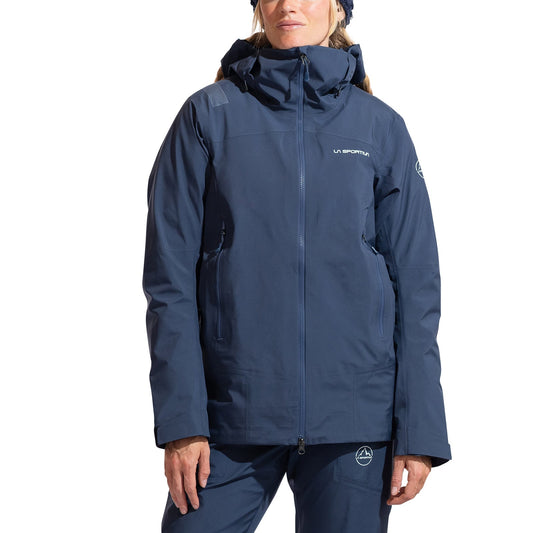 A woman wearing the La Sportiva Alpine Guide GTX Performance Jacket in navy blue, featuring a front zipper, visible pockets, and signature branding—perfect for technical mountaineering or alpine pursuits.
