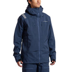 A person wears the La Sportiva Sender GTX Performance Jacket Men's in dark blue with matching pants for ski touring. The GORE-TEX jacket has a high collar, visible zippers, and a small chest logo, set against a plain white background.