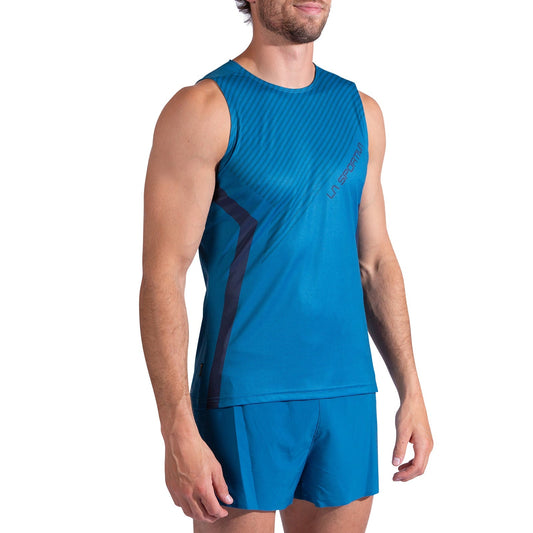 A man wears the La Sportiva Flow Tank Men's running shirt and matching blue shorts, standing slightly sideways with his arms relaxed at his sides.