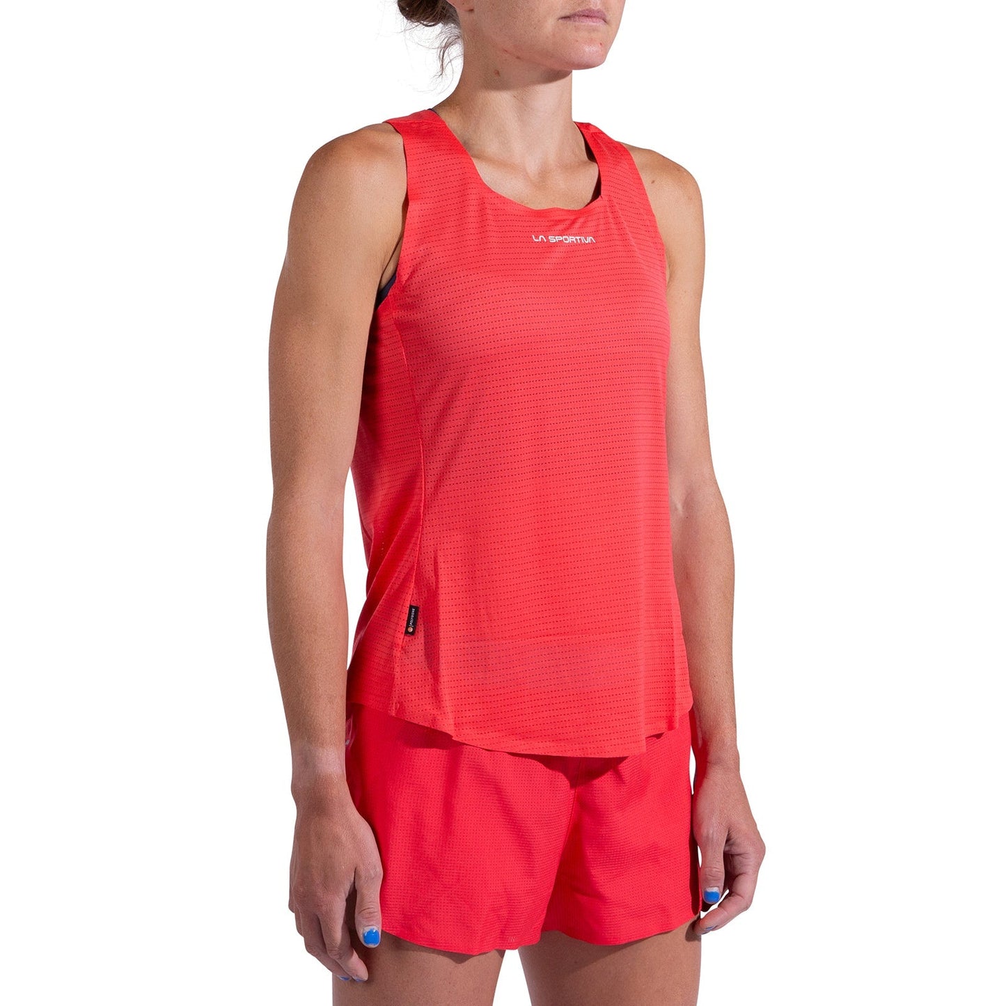 A woman wears the Pure Tank Women's by La Sportiva with matching red shorts, standing against a white background. This sporty, lightweight top is quick-drying and ideal for running or other physical activities.