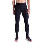 A person in La Sportiva Triumph Tight Pants Women's, made from recycled fabric, and multicolored running shoes stands against a white background with their upper body out of frame.