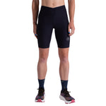 A person wearing La Sportiva Triumph Tight Shorts Women's, crafted from recycled fabric, with dark socks and colorful running shoes, stands facing forward against a white background, arms relaxed at their sides.