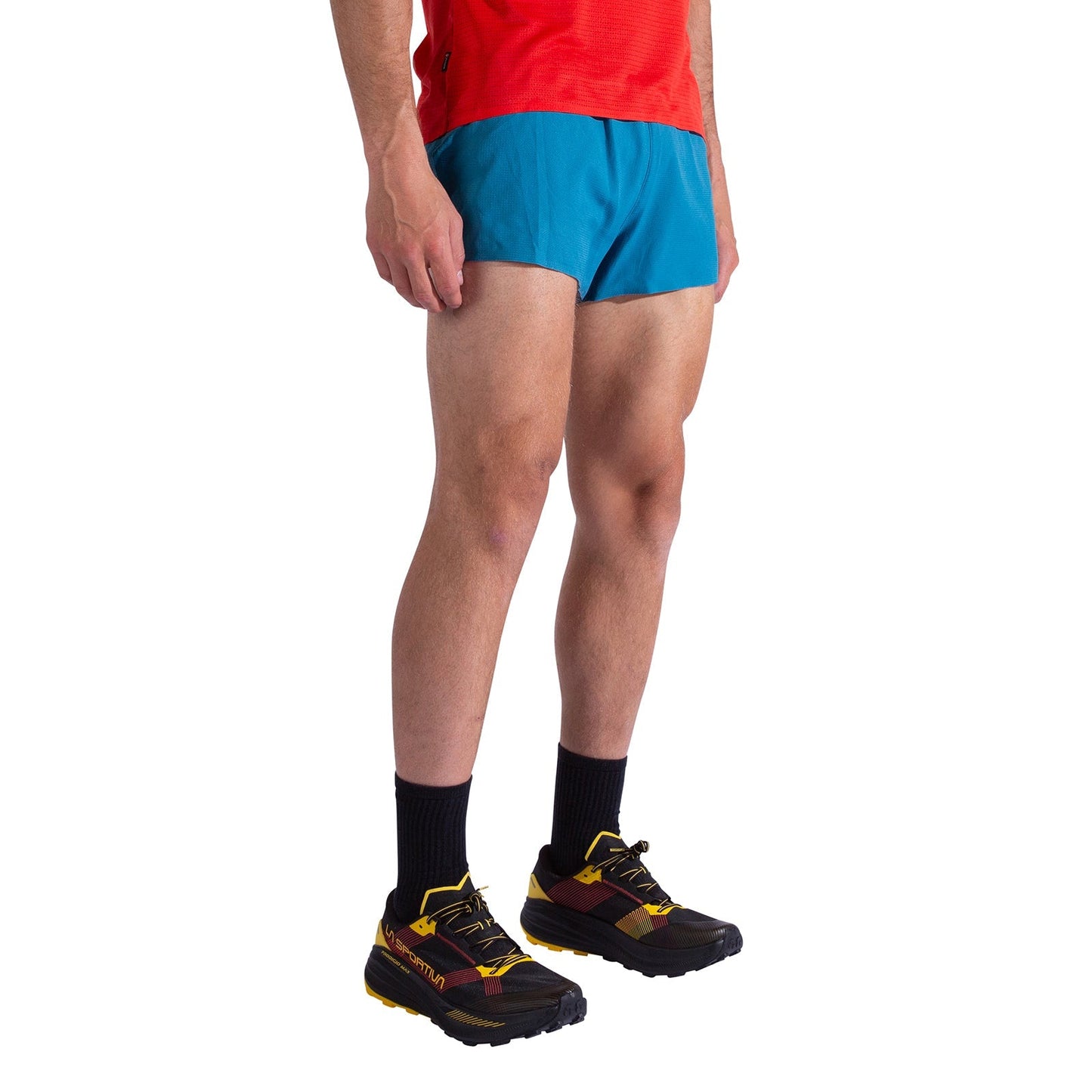 A person in a red shirt, La Sportiva Pure 3 Inch Shorts Men's (blue), black socks, and black/yellow running shoes stands against a plain white background.