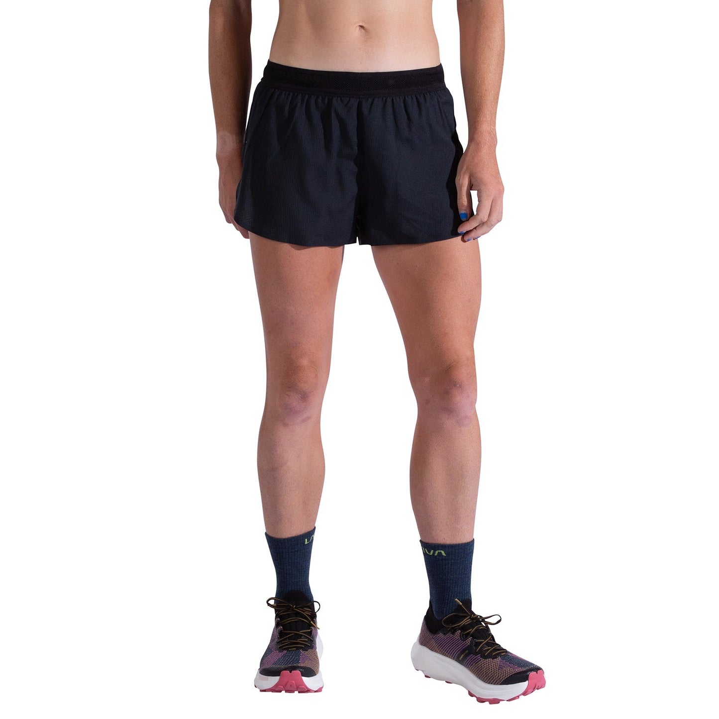 A person wearing La Sportiva Pure 3 Inch Shorts Women's, navy socks, and white running shoes with pink and black accents; the image is cropped from the chest down to show only the lower torso and legs.