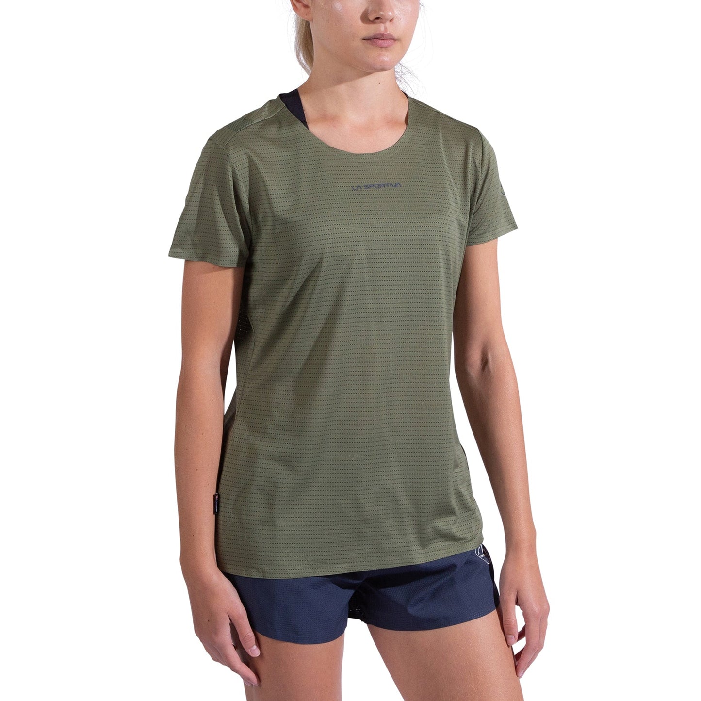 A woman wearing the La Sportiva Pure T-Shirt Women's in olive green, made from recycled polyester, and navy blue shorts stands against a plain white background.