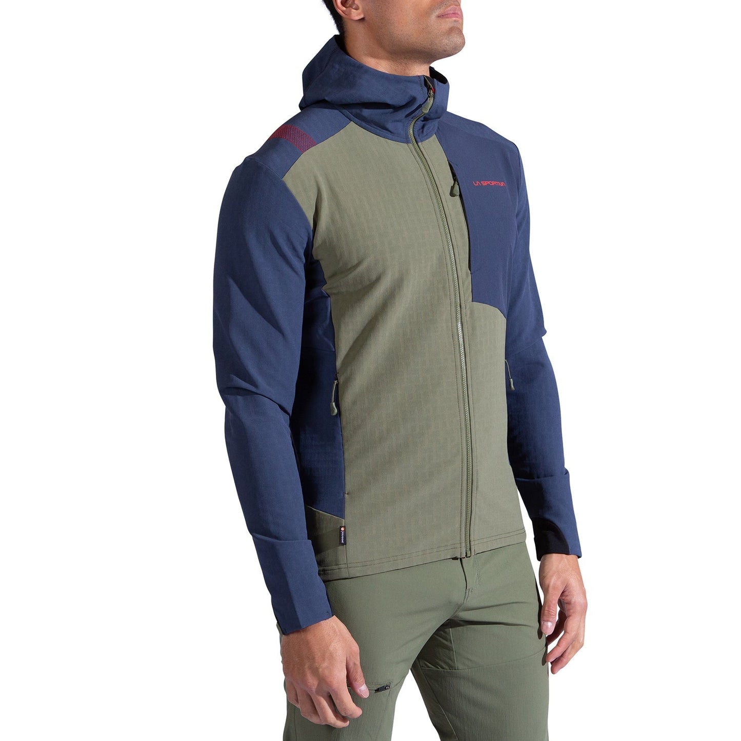 A man wearing the La Sportiva Descender Storm Jacket Men's, featuring an olive green front and sleeves with navy blue shoulders, sleeves, and hood, paired with matching olive green pants, stands against a white background.