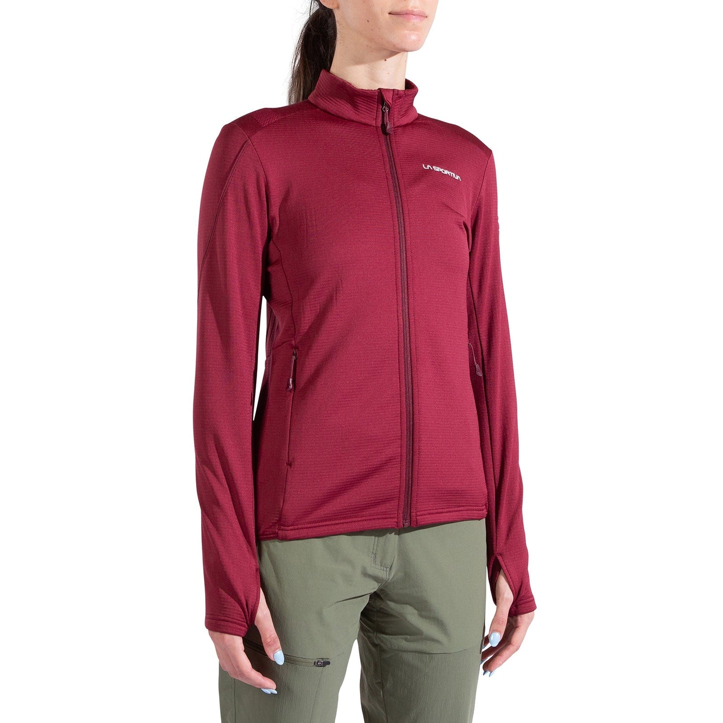A woman wearing a maroon La Sportiva Chill Thermal Jacket Women's with thumb holes and olive green pants, standing against a white background.