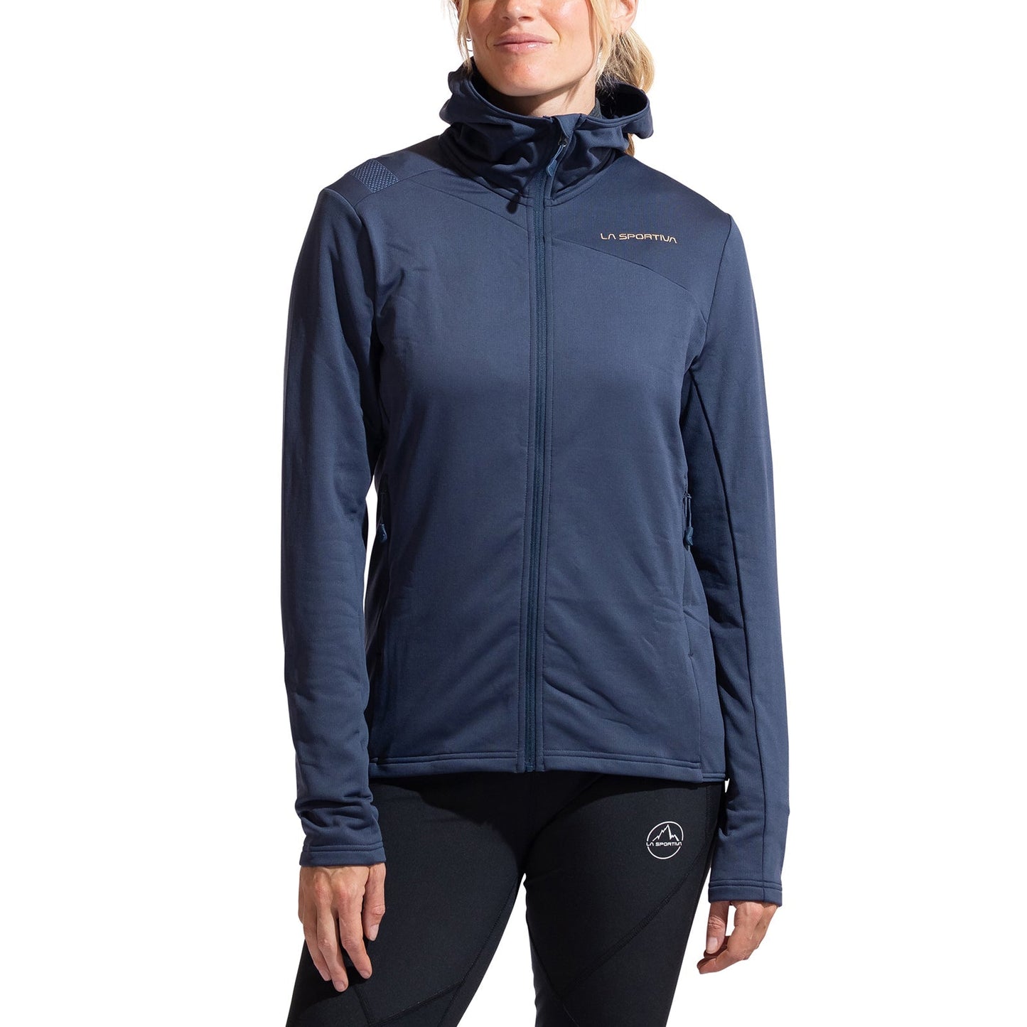 A woman stands facing forward against a white background, wearing the La Sportiva Cosmic Thermal Hoody Women's in dark blue and black leggings, hands by her sides, ready for outdoor activities.