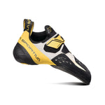 The La Sportiva Solution, a yellow, black, and white downturned climbing shoe with Velcro straps, is shown from the side against a white background. It features an aggressive curved design and Vibram XS Grip2 for precision climbing.