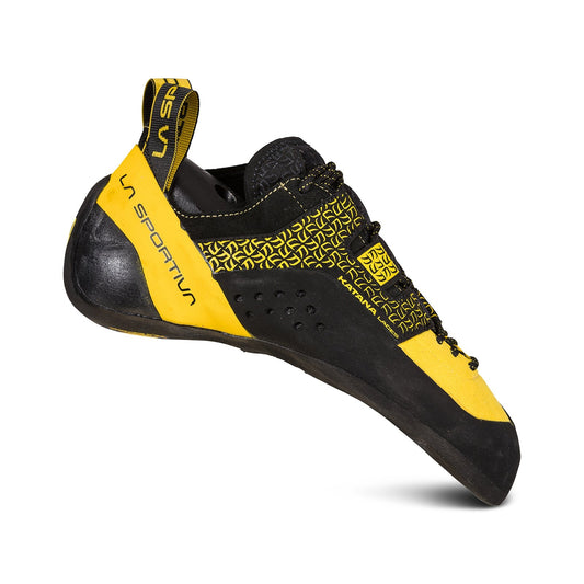 A side view shows the La Sportiva Katana Lace climbing shoe in yellow and black, featuring a lace-up design for precision, a grippy textured sole, and a heel pull tab with the La Sportiva logo.