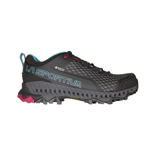 The La Sportiva Spire GTX Women's is a black and dark gray backpacking shoe with blue accents, red eyelets, teal lining, rugged sole, and Gore-Tex Surround label for reliable waterproof hiking.