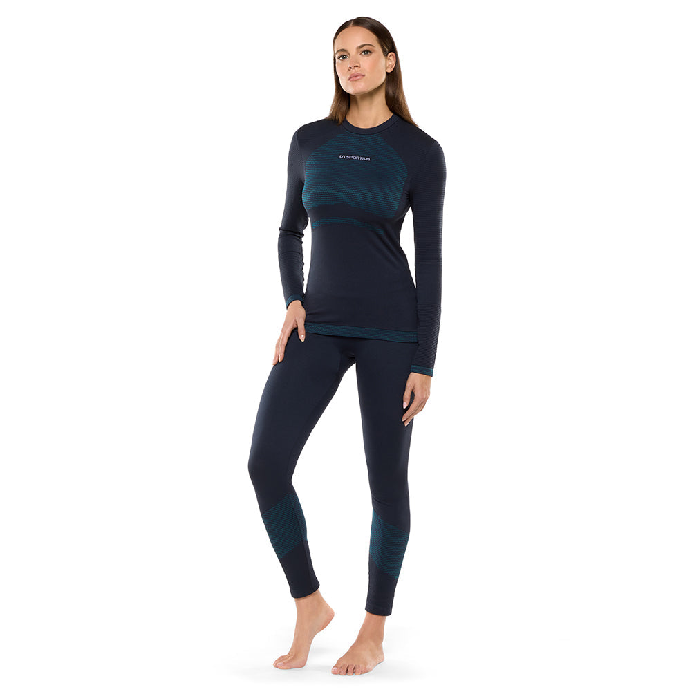 Woman modeling La Sportiva Synth Light Pants Women's, navy blue winter aerobic tights with teal stripe accents, breathable long tight design and Polygiene treatment, on a white background.