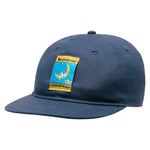 The La Sportiva Climbing On The Moon Hat (2025) is a dark blue organic cotton cap with a colorful patch showing the logo, an illustration of a figure climbing a crescent moon, and the text “Climbing on the Moon.”.